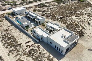 A modern, multi-story building with a flat roof, a swimming pool, and a large patio area.