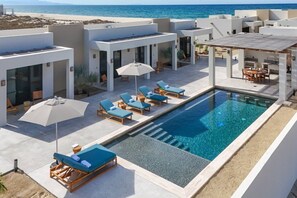 Ein Dachpool mit Liegestühlen und Sonnenschirmen mit Blick auf einen Strand.