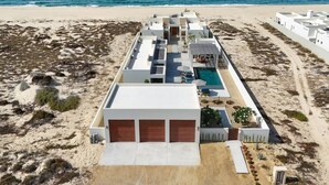 A beachfront hotel with multiple white buildings, a swimming pool, and a sandy beach. - Oceanfront Luxury in East Cape Private Beachfront (Ligth House Point States)