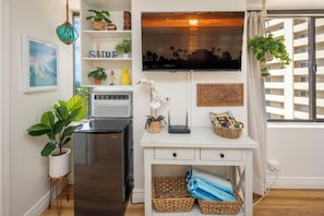Eine moderne Küche mit einem Kühlschrank, einem Flachbildfernseher und diversen Pflanzen.