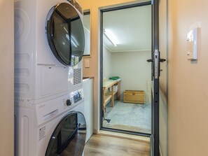 Ein Waschbereich mit gestapelten Waschmaschinen und Trocknern, einer Holzbank und einem Korbwäscheschrank.
