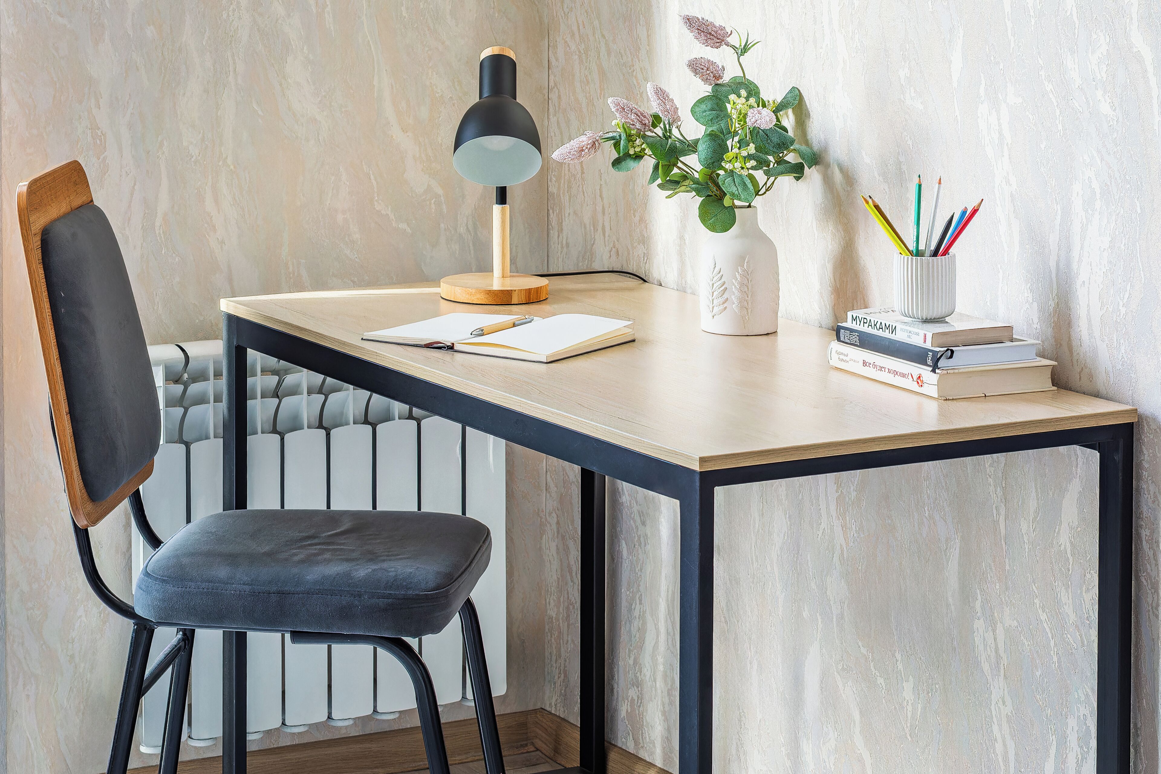 A desk with a lamp, a chair, a plant, and books.