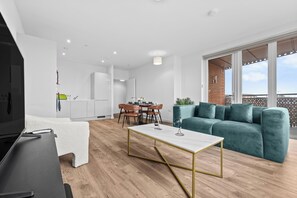 Ein modernes Wohnzimmer mit Fernseher, einer Couch, einem Essbereich und einem Balkon mit Aussicht.