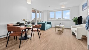 Ein modernes Wohnzimmer mit Essbereich, einer Couch, einem Couchtisch und einem Fernseher.