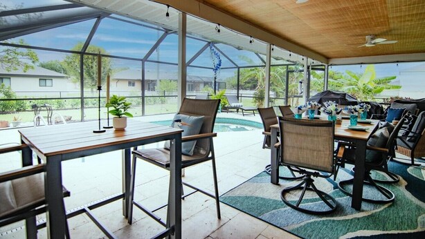Un espacio al aire libre cubierto con piscina, sillas y una mesa.