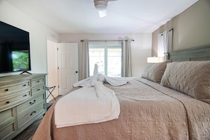 Une chambre d’hôtel avec un lit, une télévision, une commode et une fenêtre avec des rideaux.