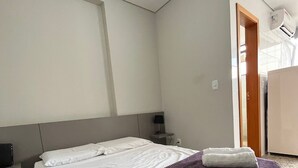 A hotel room with a bed, a nightstand, a lamp, and a door leading to a bathroom. - LK Lourdes 11 (Belo Horizonte)