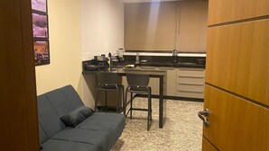 A compact kitchen with a dining area, a sofa, and a door. - LK Lourdes 11 (Belo Horizonte)