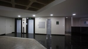 A clean, modern lobby with a polished floor, a central elevator, and a reception desk. - LK Lourdes 11 (Belo Horizonte)