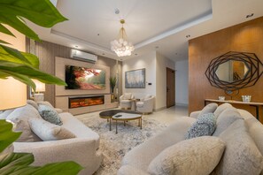 Una sala de estar moderna con chimenea, asientos cómodos, un televisor grande y un espejo decorativo.