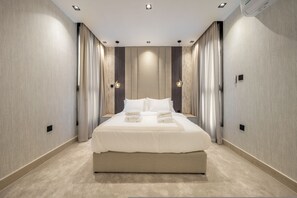 Una habitación de hotel moderna con una cama grande, un televisor de pantalla plana y aire acondicionado integrado.