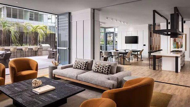 Ein modernes Wohnzimmer mit einer Couch, Sesseln, einem Couchtisch und einem Essbereich mit einem Fernseher.