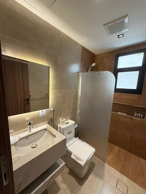A modern bathroom with a large mirror, a sink, a toilet, and a shower. - AYA Inn  (Jeddah)