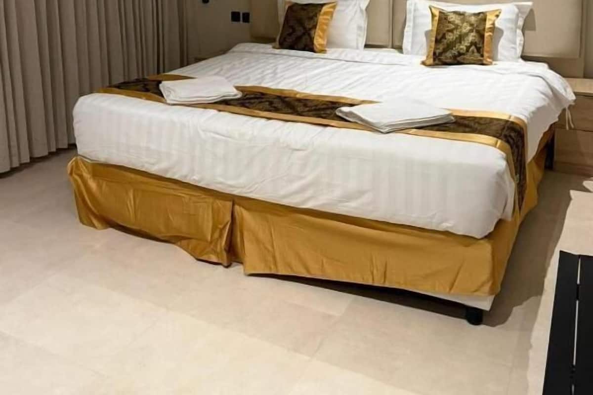 Una habitación de hotel moderna con una cama grande, una mesita de noche y una lámpara de pared.