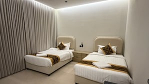 Quarto de hotel moderno com duas camas, uma mesinha e ar condicionado fixado na parede.