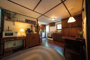 A kitchen with wooden cabinets, a microwave, a coffee station, and a dining area with a table and chairs.