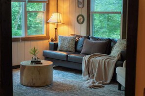 A cozy living room with a sofa, a round coffee table, and a lamp.