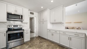 A modern kitchen with white cabinetry, stainless steel appliances, and a tiled floor. - Premier 3-Bedroom Condo in Coveted Indian Wells Country Club, Discounted Rates! (Indian Wells)