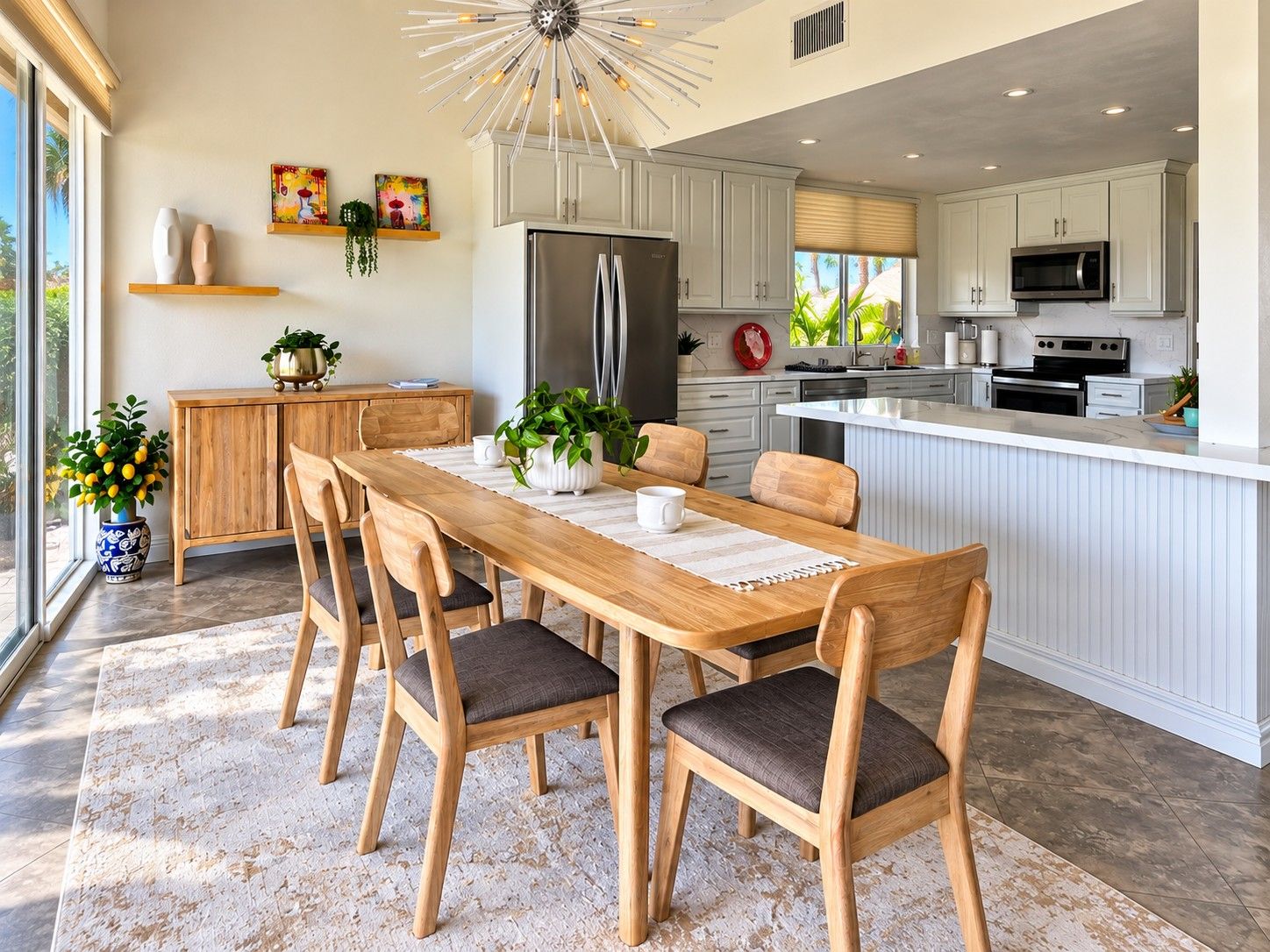 A modern kitchen with a central island, white cabinetry, and a dining area with wooden chairs and a table.