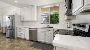 A modern kitchen with white cabinets, stainless steel appliances, and a large window. - Premier 3-Bedroom Condo in Coveted Indian Wells Country Club, Discounted Rates! (Indian Wells)
