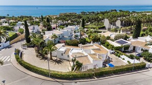 A coastal residential area with white buildings, palm trees, and a clear view of the sea. - The Beach House - Villa walking to the beach (Albufeira)