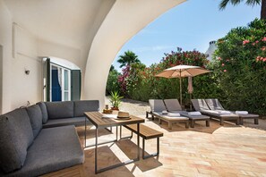 An outdoor patio with a sofa, a table, and lounge chairs. - The Beach House - Villa walking to the beach (Albufeira)