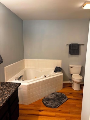 Une salle de bain avec une baignoire, des toilettes et un comptoir en granit.
