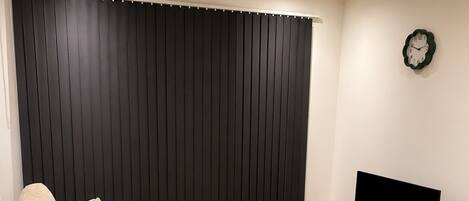 Una sala de estar con sofá, mesa de centro, mueble para televisión y un reloj en la pared.