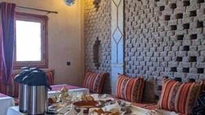Un comedor con una mesa dispuesta para una comida, una lámpara colgante y una pared de ladrillo con un diseño geométrico.