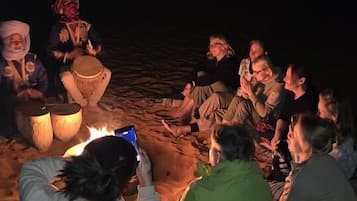 Eine Gruppe von Menschen sitzt am Abend an einem Lagerfeuer.