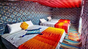 Una habitación con dos camas, paredes con estampado y un dosel rojo.