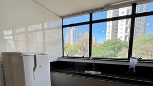 A kitchen with a refrigerator, sink, and window overlooking a cityscape. - LK Lourdes 9 (Belo Horizonte)