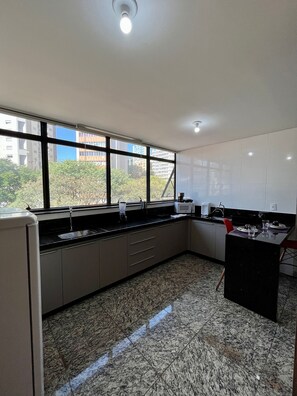 Una cocina moderna con ventanas amplias, encimera de granito y vistas a edificios.