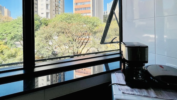 A kitchen with a window view of tall buildings and trees. - LK Lourdes 9 (Belo Horizonte)