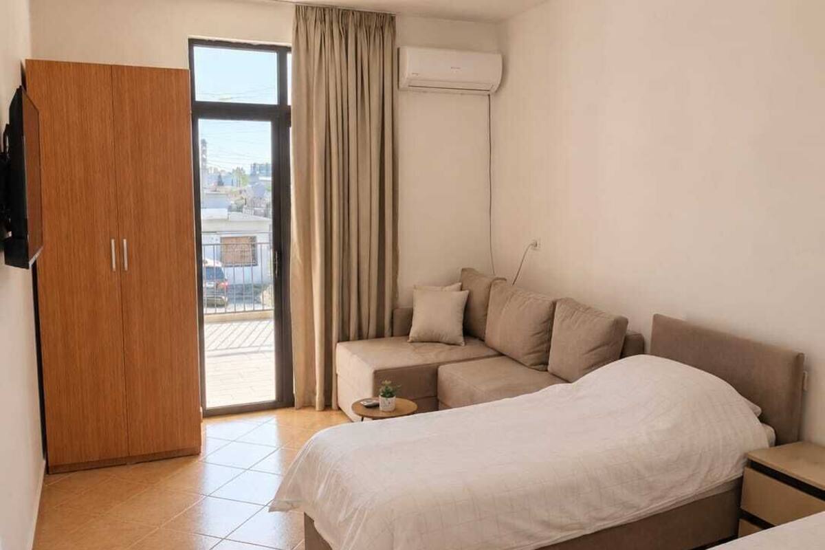 Hotelkamer met een bed, een bank, een kleine tafel, een kledingkast en een schuifdeur naar buiten.
