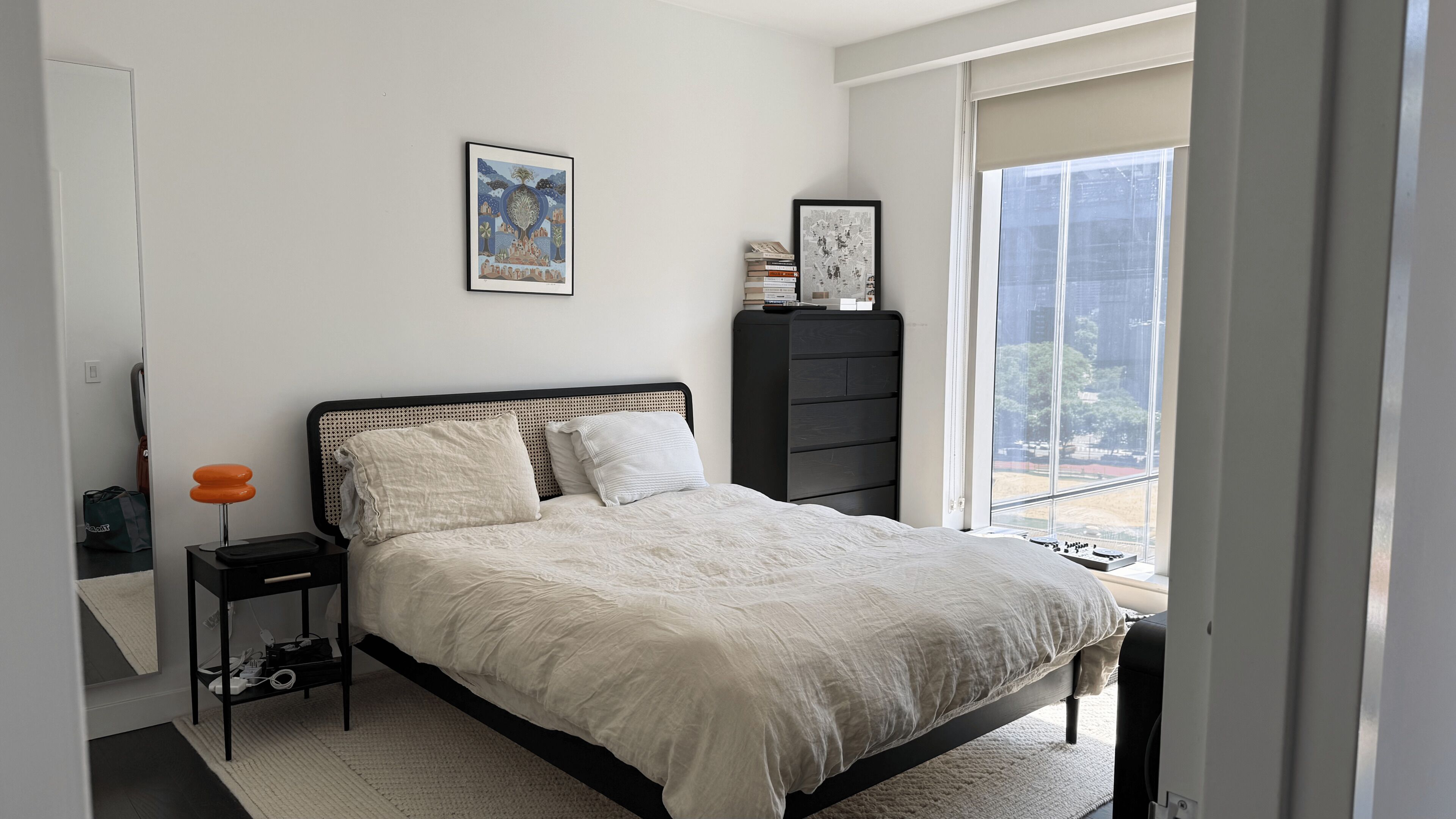 Un dormitorio con cama, mesita de noche, cómoda, ventana con vistas y puerta.