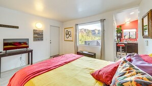 Ein Schlafzimmer mit Bett, Fernseher, Schreibtisch, Fenster mit Blick und angrenzendem Badezimmer.