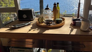 Un bureau en bois sur lequel se trouvent un grille-pain, un bocal en verre, une bouteille, une tasse et une boîte de sucre d’érable.