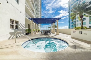 Une piscine sur le toit, agrémentée d’une pergola bleue, de coins salon extérieurs et offrant une vue sur un immeuble de grande hauteur.