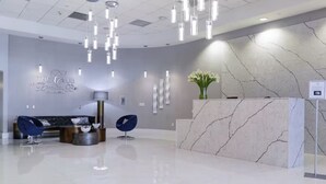 Een moderne receptie met een marmeren receptiebalie, een bank en een blauwe stoel.