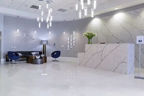 Una zona de recepción moderna con un mostrador de mármol, un sofá y una silla azul.
