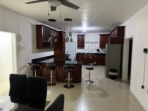 A modern kitchen with a central island, bar stools, and a ceiling fan. - Runaway Dreams Jamaica – Your Private Paradise Awaits (Runaway Bay)