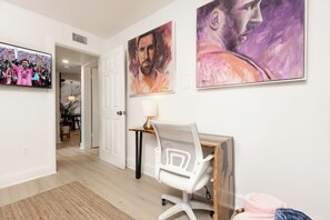 Une chambre moderne équipée d’un bureau, d’une chaise et d’une œuvre d’art au mur.