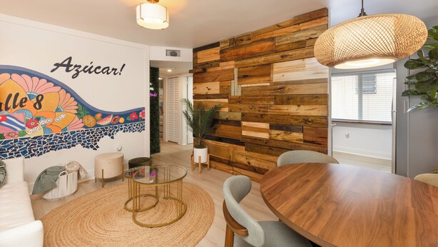 A modern interior with a wooden wall, a round dining table, a glass coffee table, and a wall mural. - "Boutique Art Home"  Little Havana King Bed,Near Brickell,Airport & South Beach (Miami)