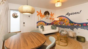 A room with a round wooden table, a white sofa, a hanging woven light fixture, and a colorful mural on the wall. - "Boutique Art Home"  Little Havana King Bed,Near Brickell,Airport & South Beach (Miami)