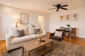 Un salon comprenant un canapé, un fauteuil, une table basse et un coin repas avec une table et des chaises.