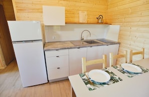 Eine kleine Küche mit Kühlschrank, Spüle und Holzschränken.