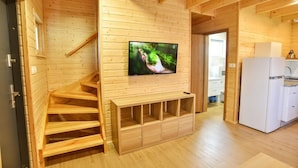 Een houten interieur met een televisie aan de muur, een trap en een keukenhoek.