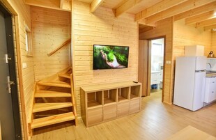 Un interior de madera con televisión en la pared, una escalera y una zona de cocina.