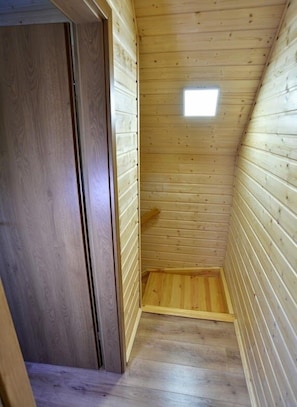 A narrow, wooden-paneled room with a small window and a door.